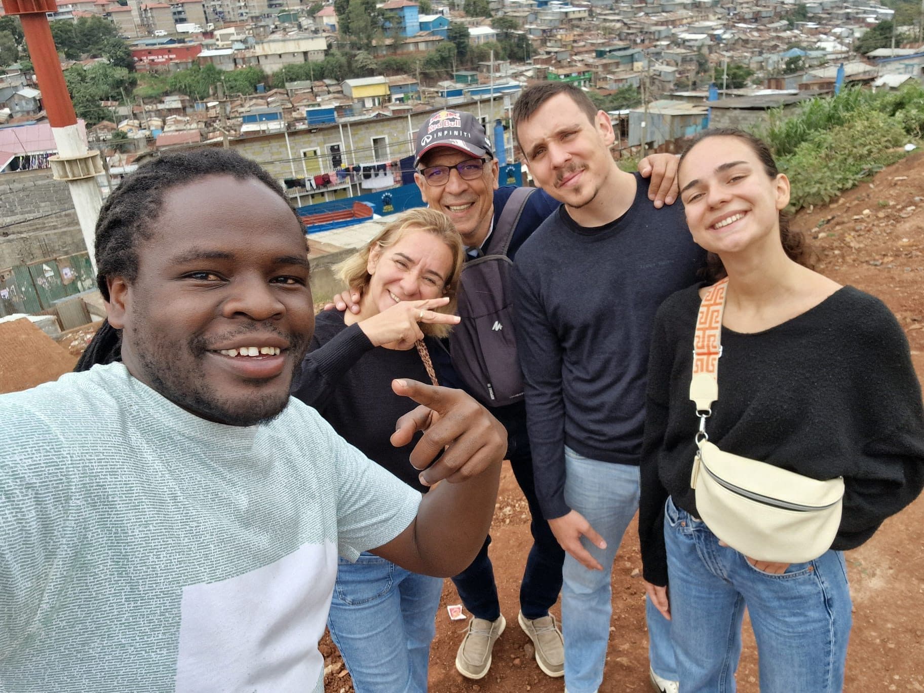 A guide and four guests at a viewpoint with the rooftops of Kibera behind them