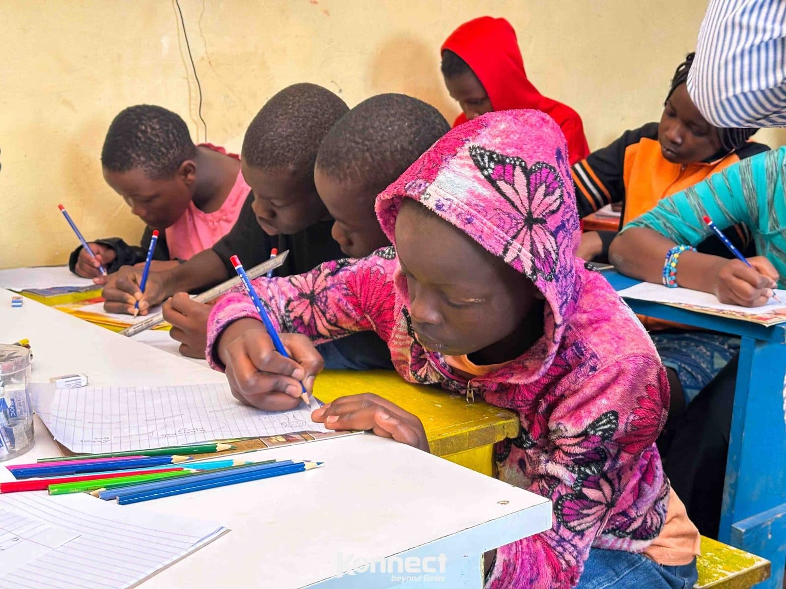 Children doing their homework at the library tables, pencils and exercise books in front of them