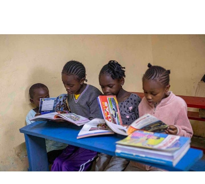 Four children reading storybooks together at a table in the library