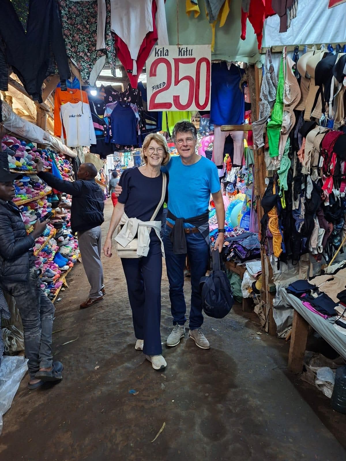 Two guests walking through a lane of clothes stalls in the market