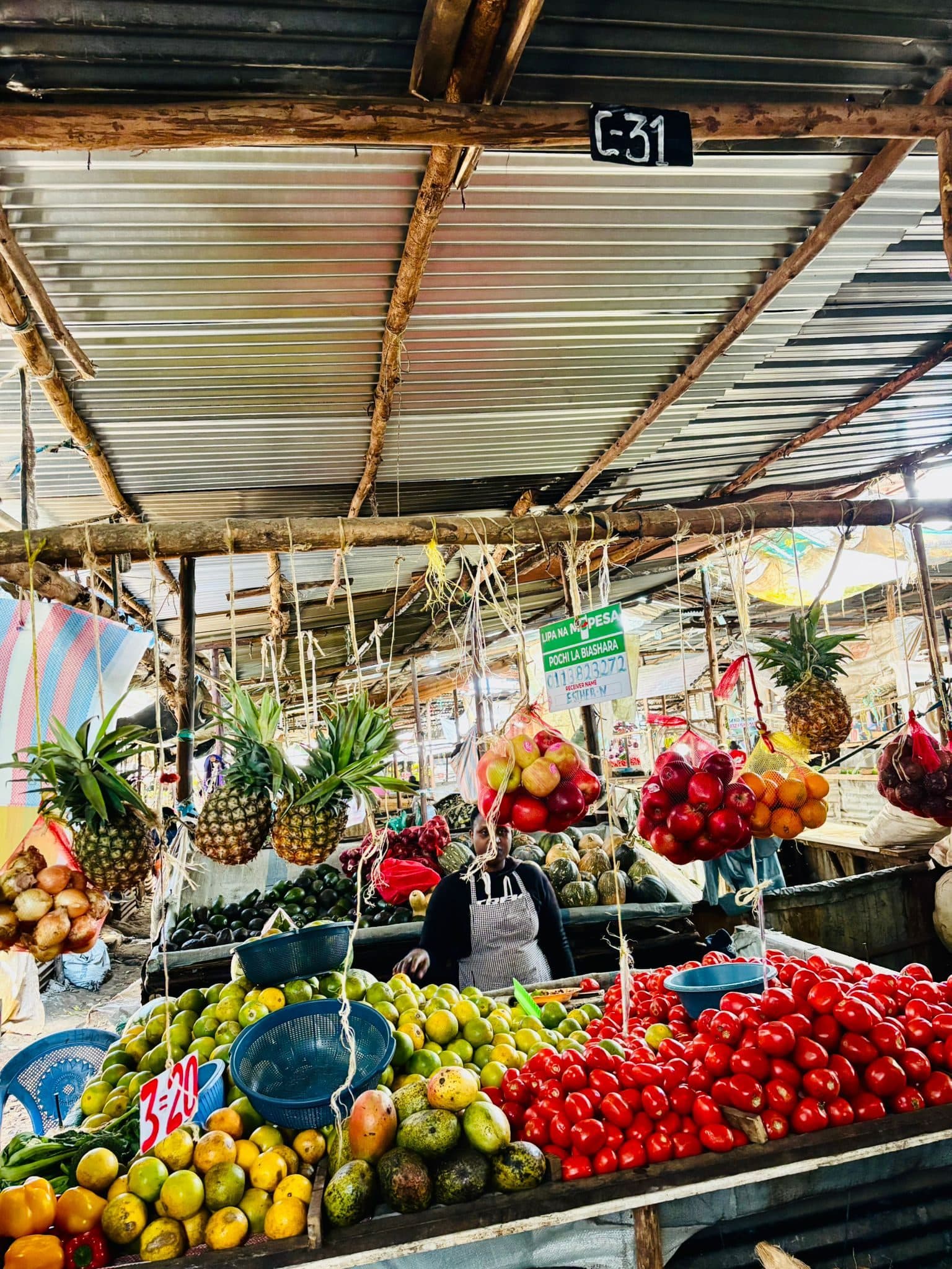 A fruit and vegetable stall in the open air market, piled with tomatoes, mangoes and pineapples
