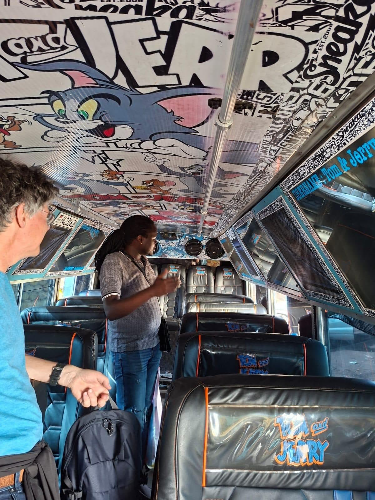 Inside a matatu, its ceiling painted with cartoons, a guest standing in the aisle